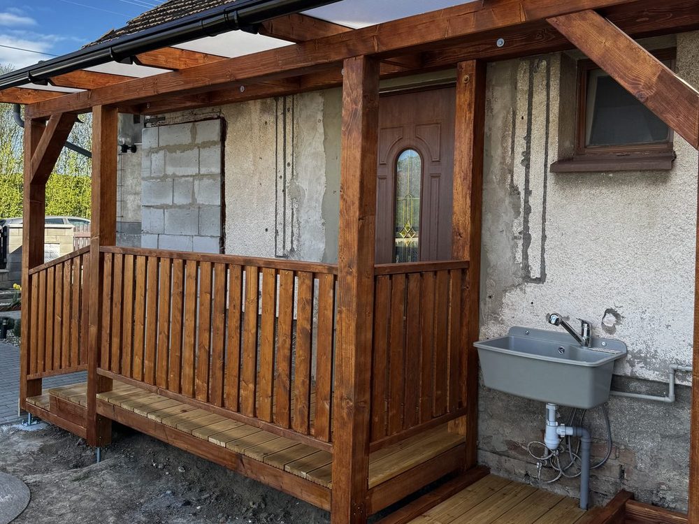 Pergola nad vstupem do domu s modřínovou podlahou a zábradlím