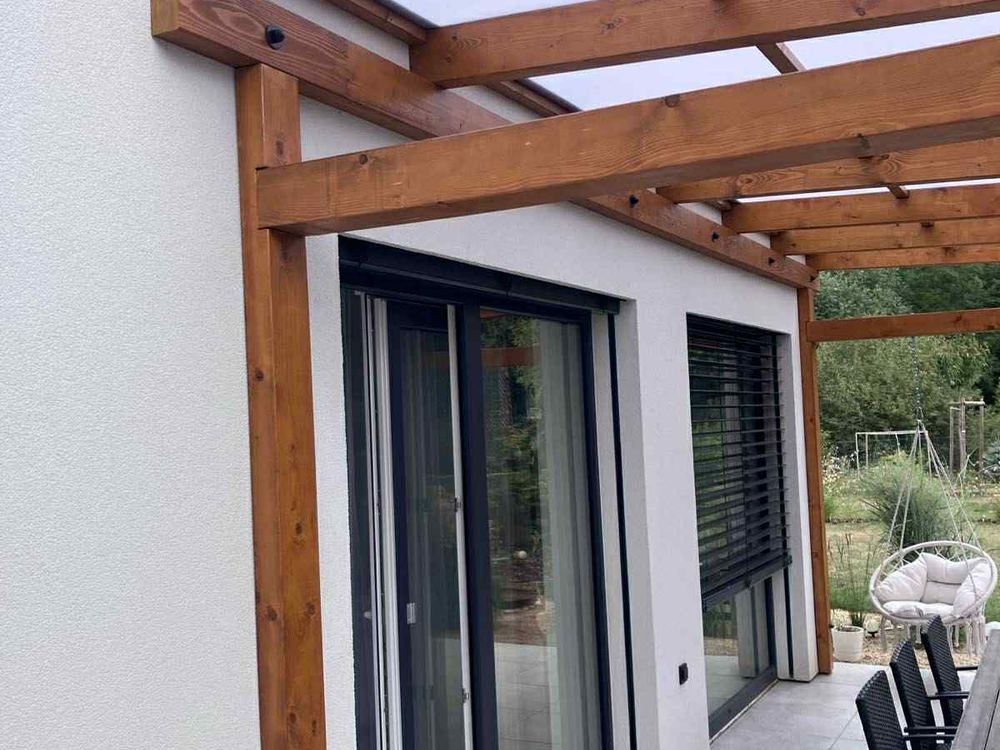 Pergola navazující na fasádu domu s velkými prosklenými dveřmi